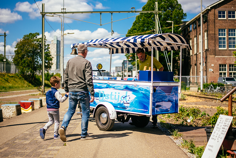 Man en kind lopen naar een mooie blauwe ijskar.