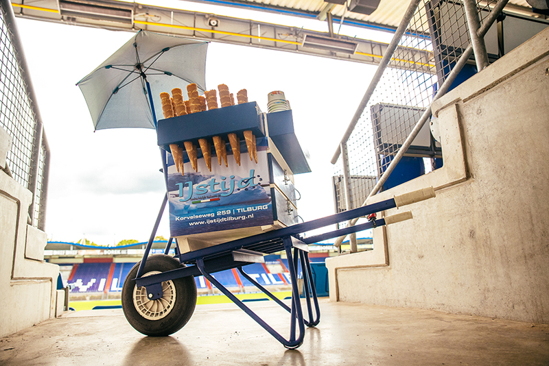 Blauw witte ijskar in kruiwagenstijl staat op de tribune van het Willem II stadion.